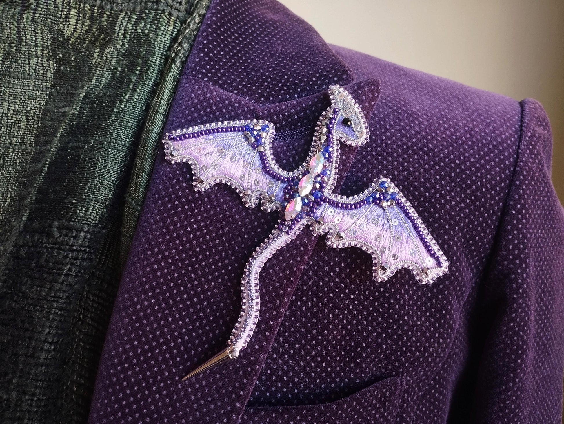 A purple jacket with a decorative dragon pin or brooch on the lapel.