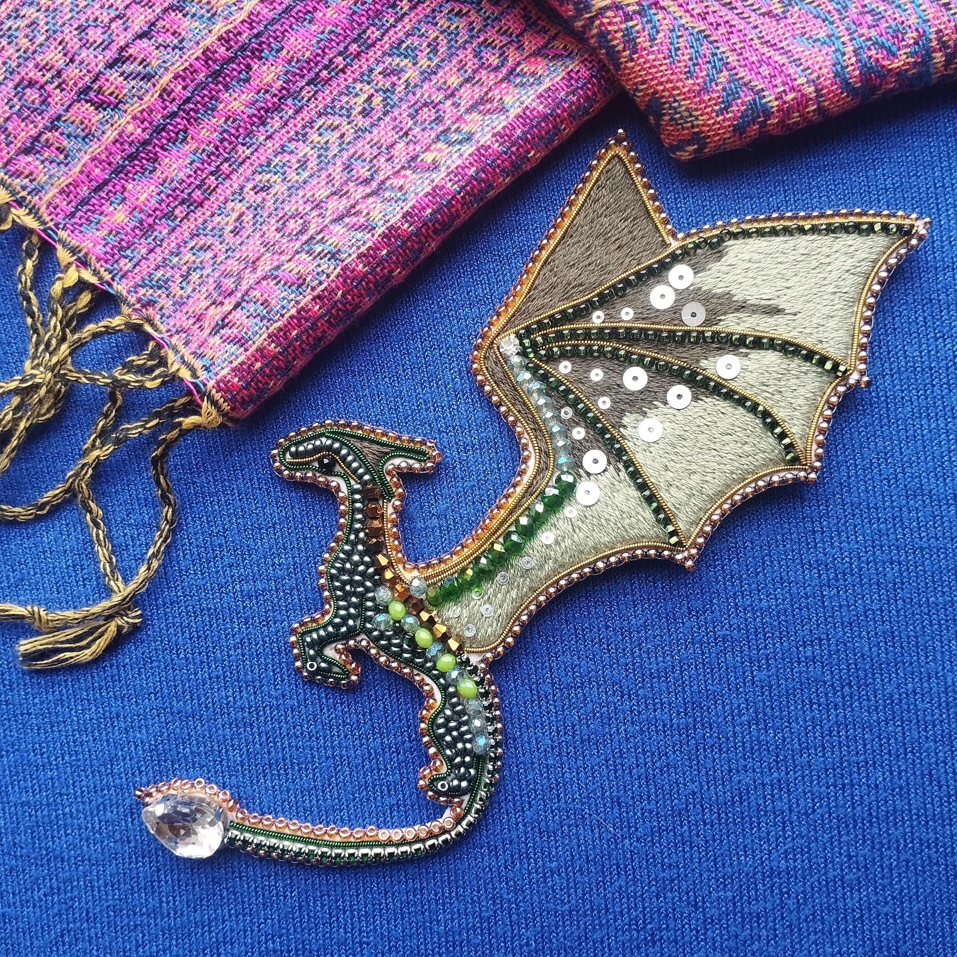a dragon-shaped object with a blue background, adorned with green and silver embellishments.