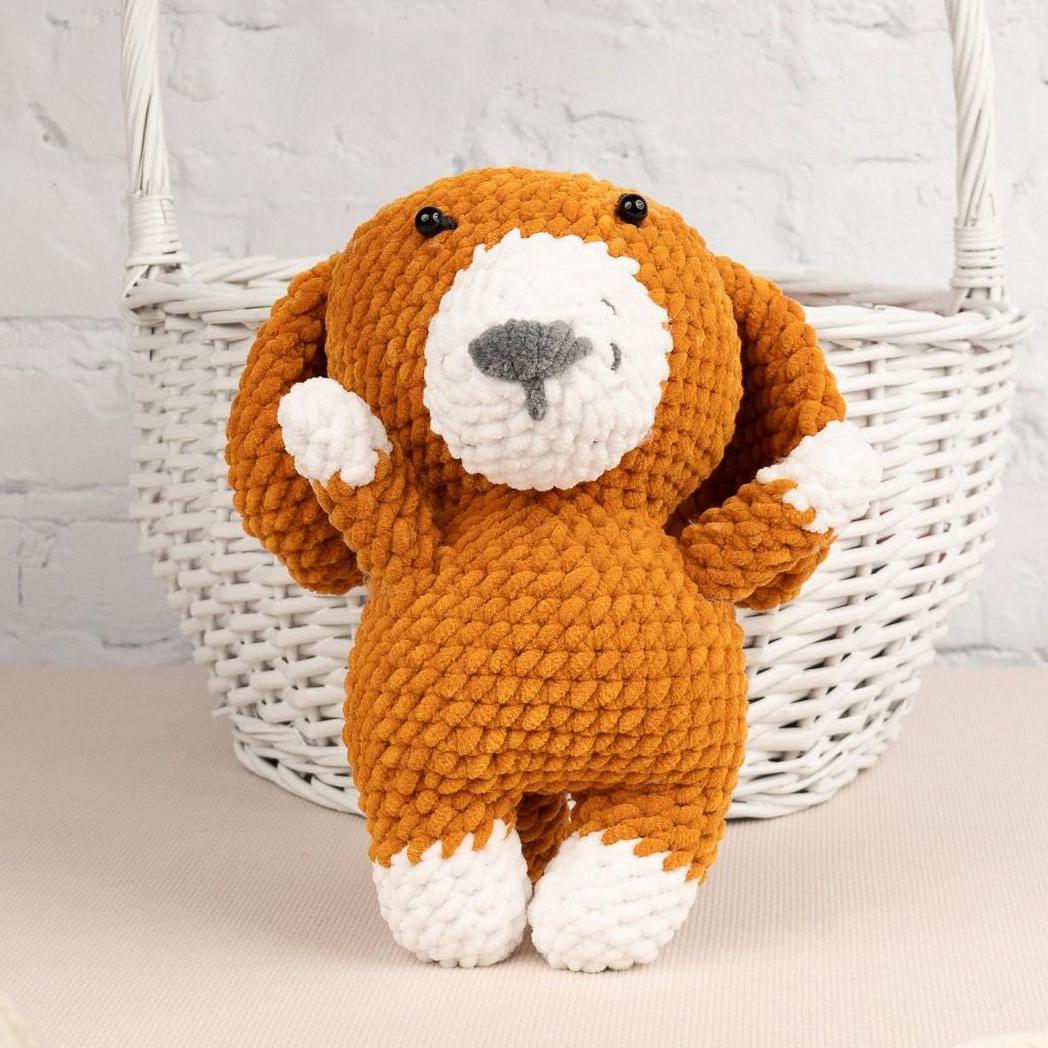 a brown and white stuffed dog sitting next to a basket