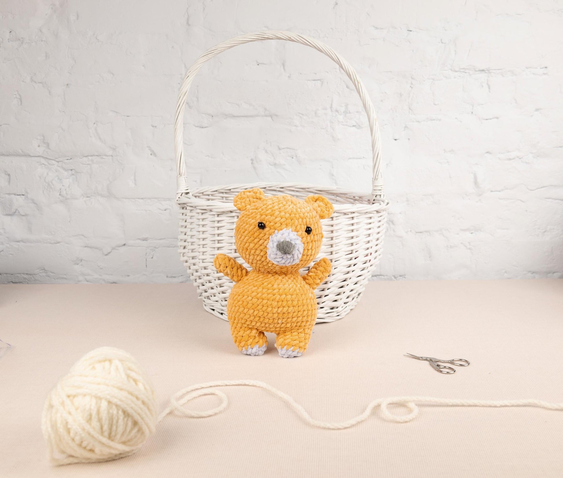 a teddy bear sitting next to a ball of yarn
