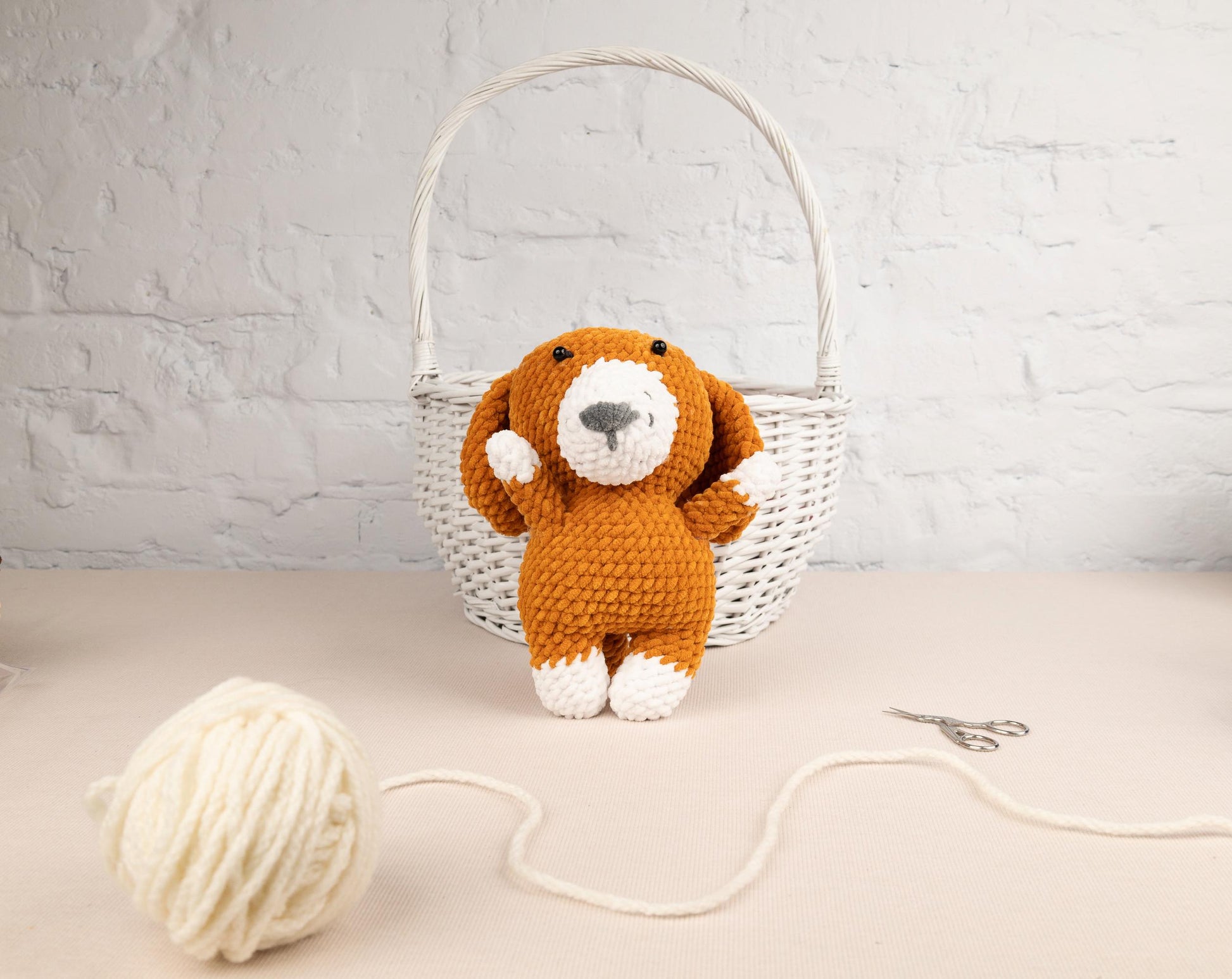 a stuffed dog sitting next to a ball of yarn