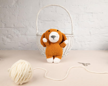 a stuffed dog sitting next to a ball of yarn