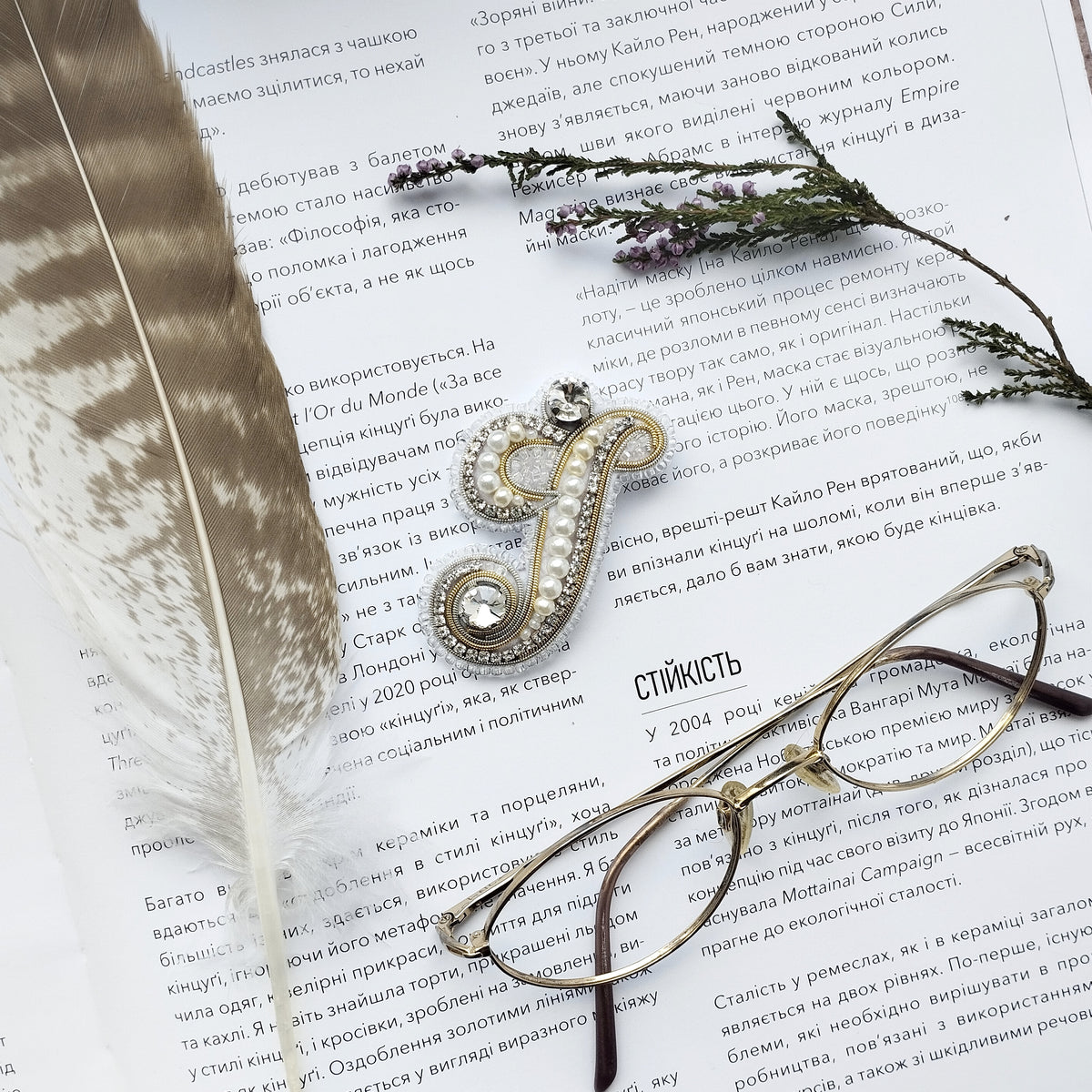 a close-up of a book with a feather and a pair of glasses resting on top of it.