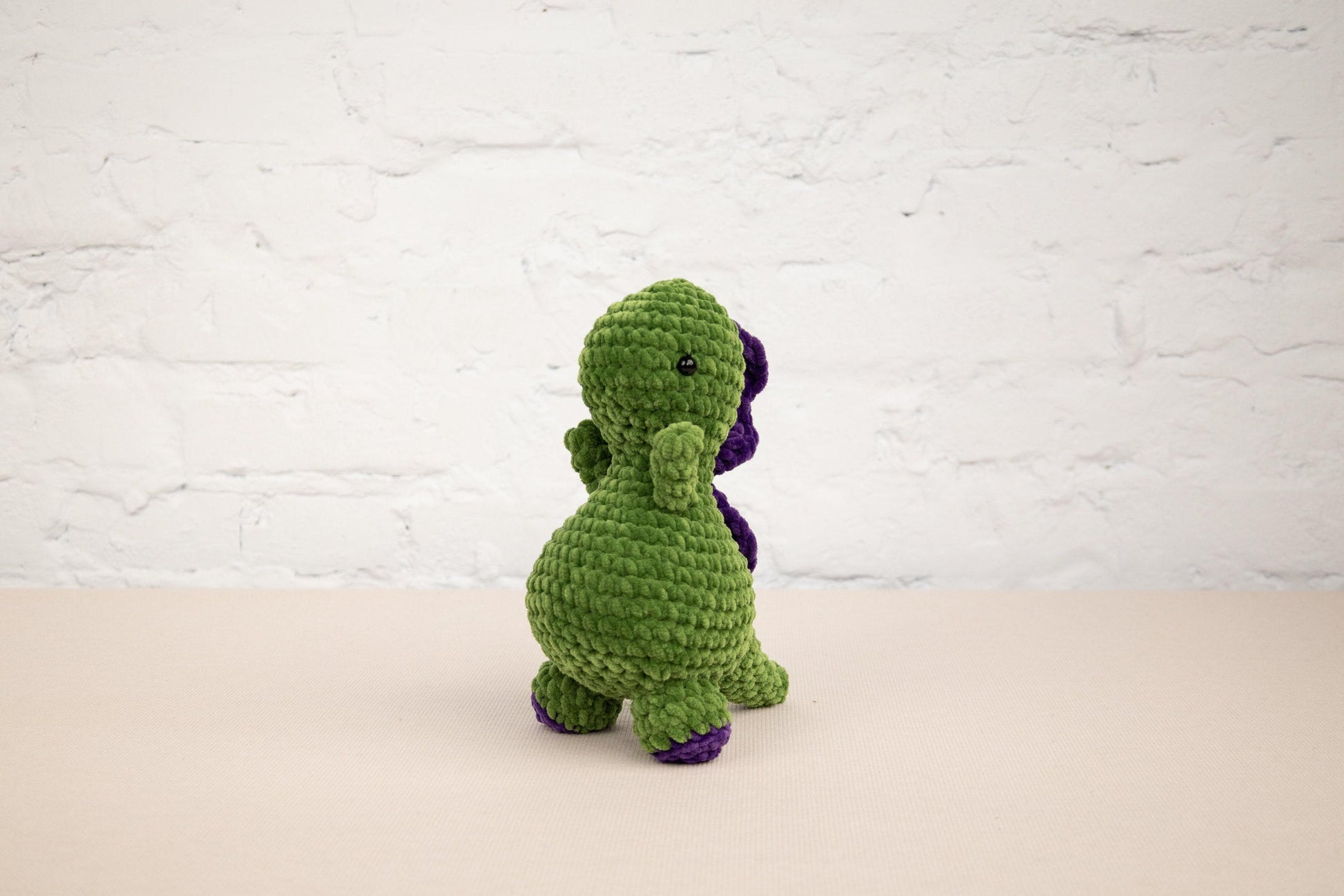 a crocheted green and purple dinosaur sitting on a table