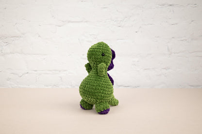 a crocheted green and purple dinosaur sitting on a table