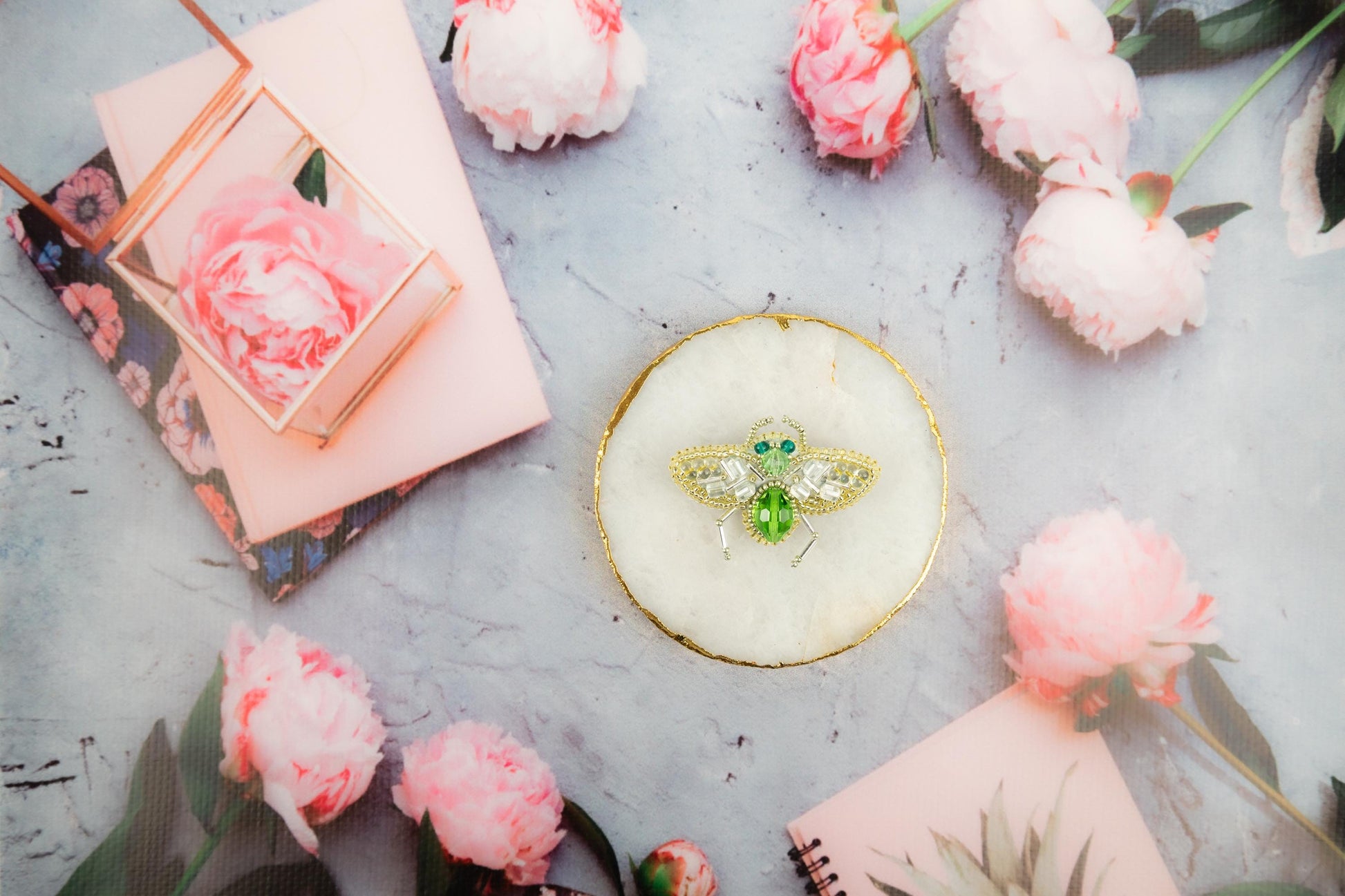 a bee brooch sitting on top of a table surrounded by flowers