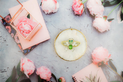 a bee brooch sitting on top of a table surrounded by flowers
