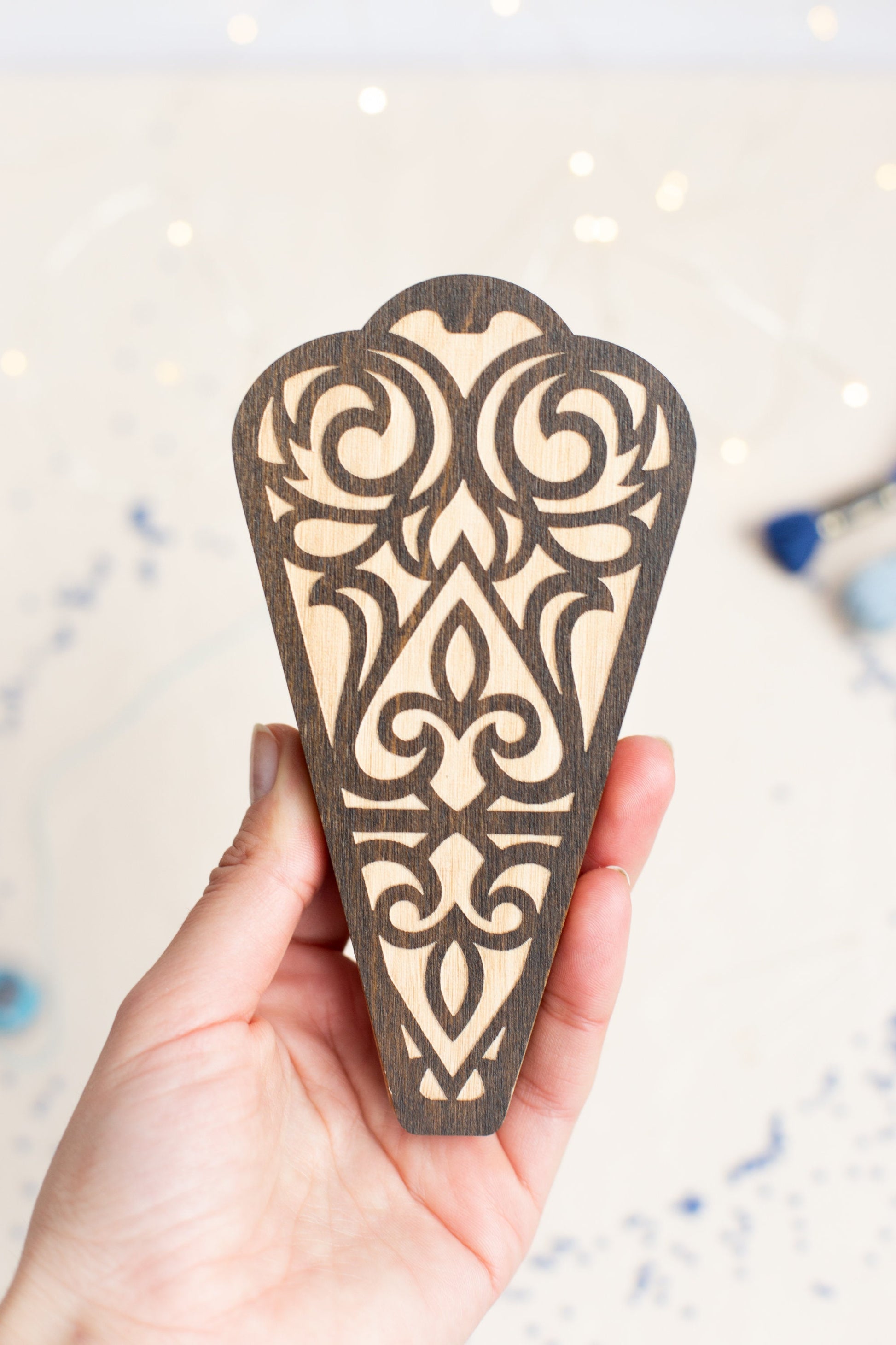 a hand holding a piece of wood with a design on it