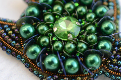 a close up of a green beaded brooch