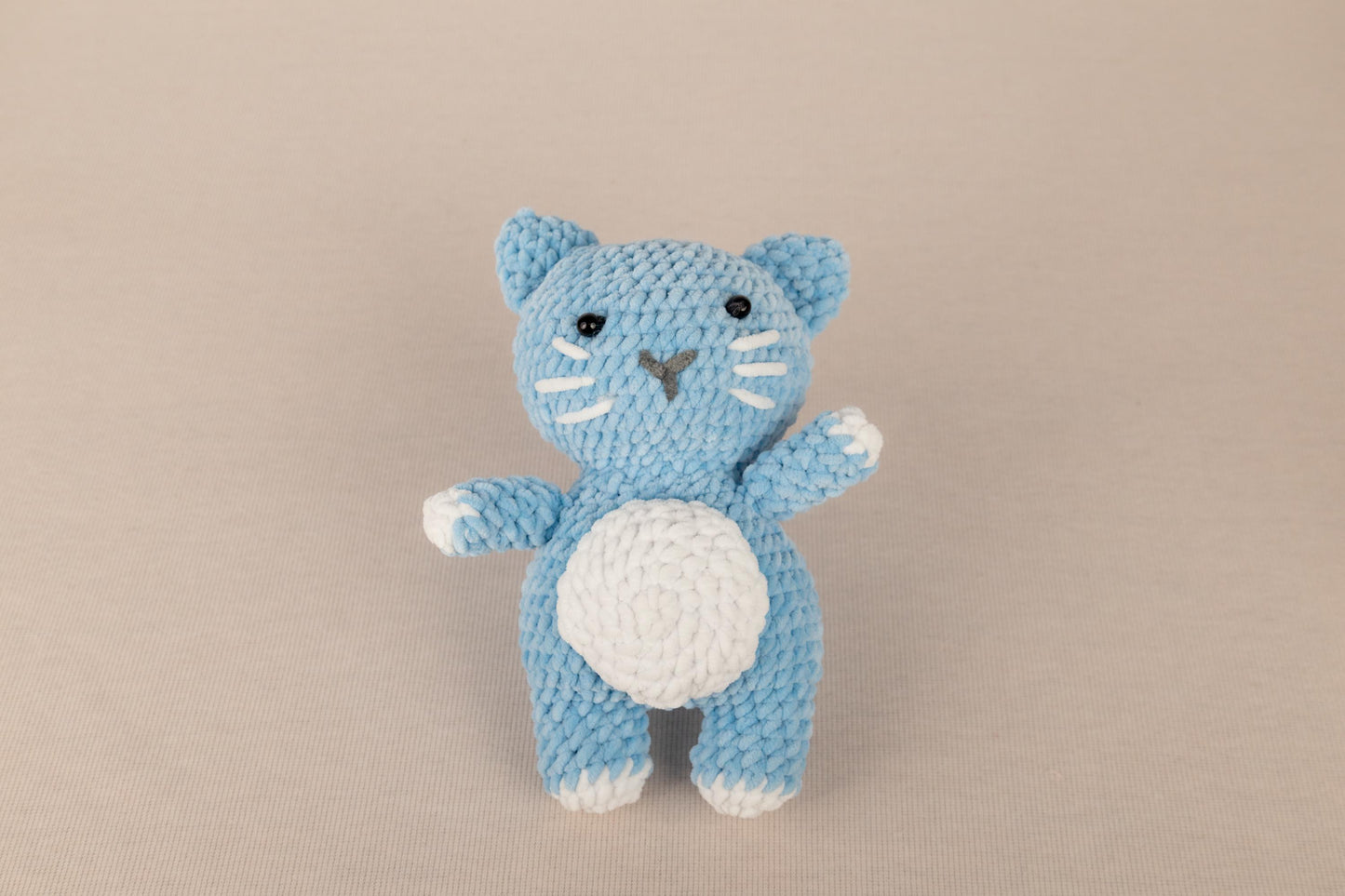 a crocheted blue cat with a white belly