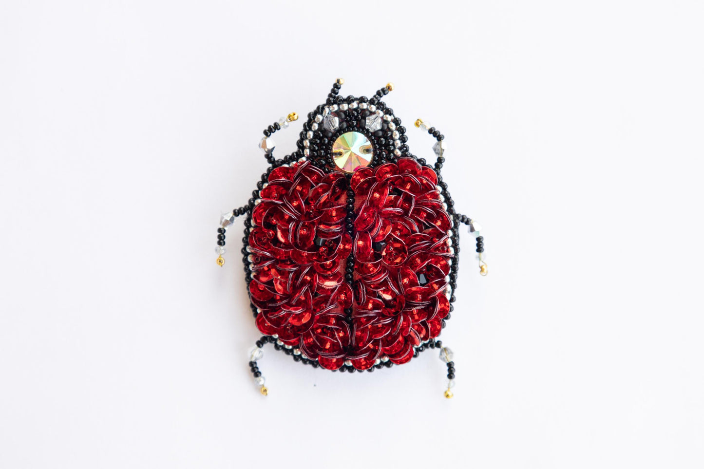 a red and black beaded bug on a white surface