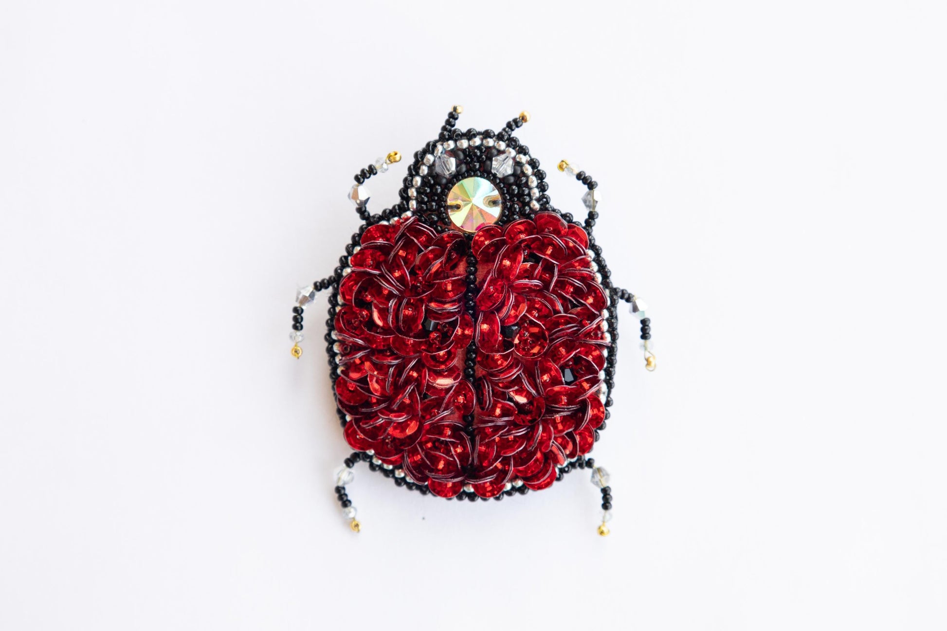 a red and black beaded bug on a white surface