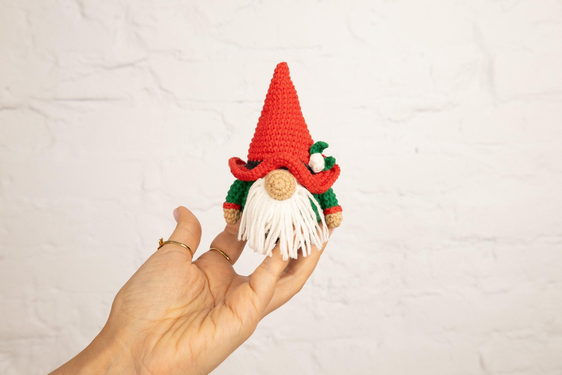 a hand is holding a small crocheted gnome