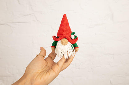 a hand is holding a small crocheted gnome