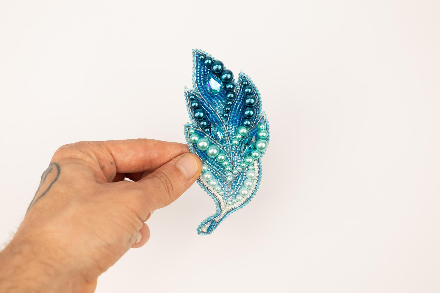 a hand is holding a beaded brooch