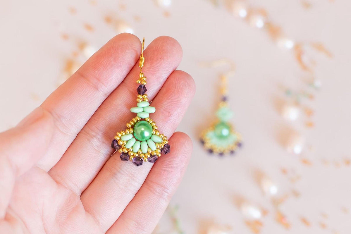 a woman's hand holding a pair of earrings