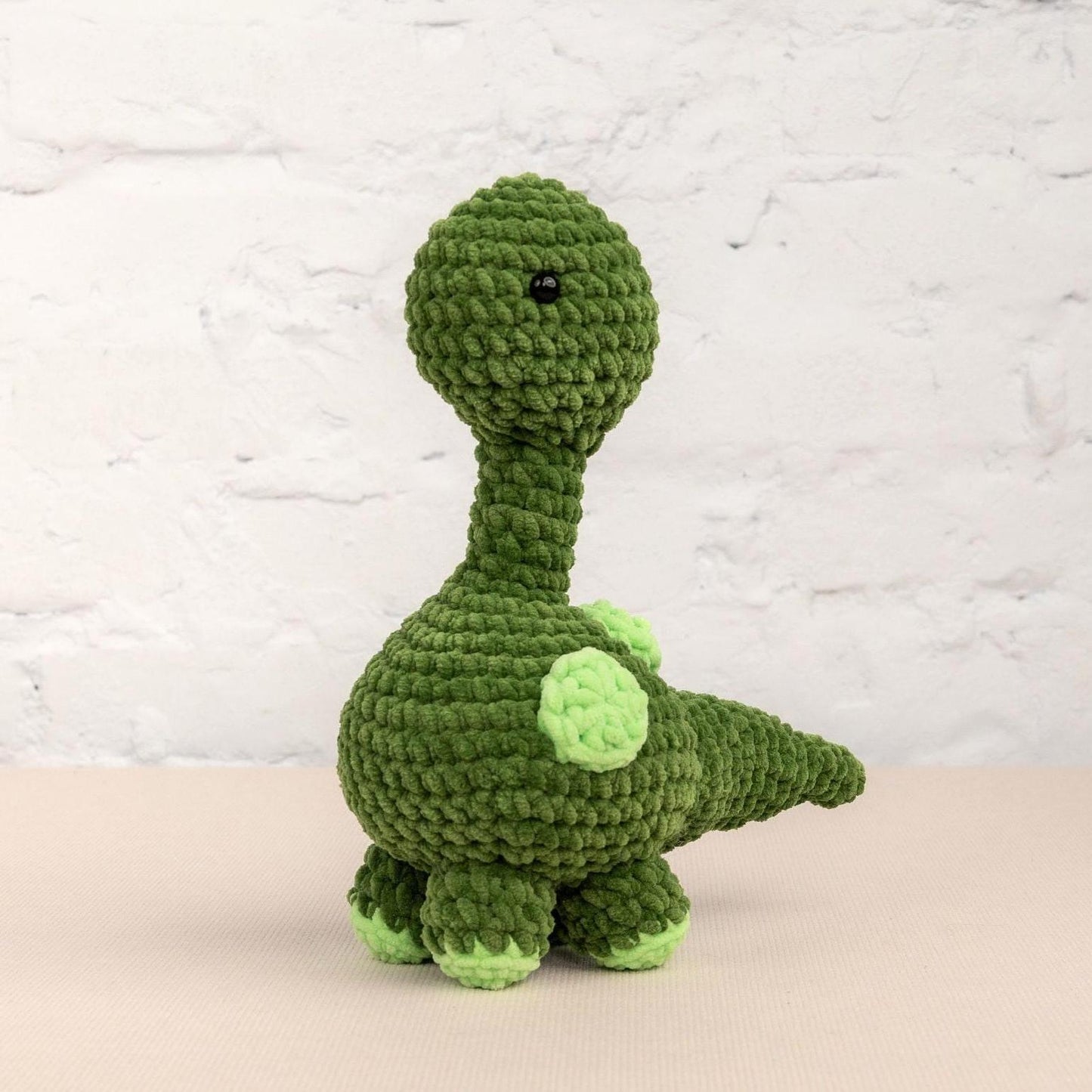 a green crocheted stuffed animal sitting on a table