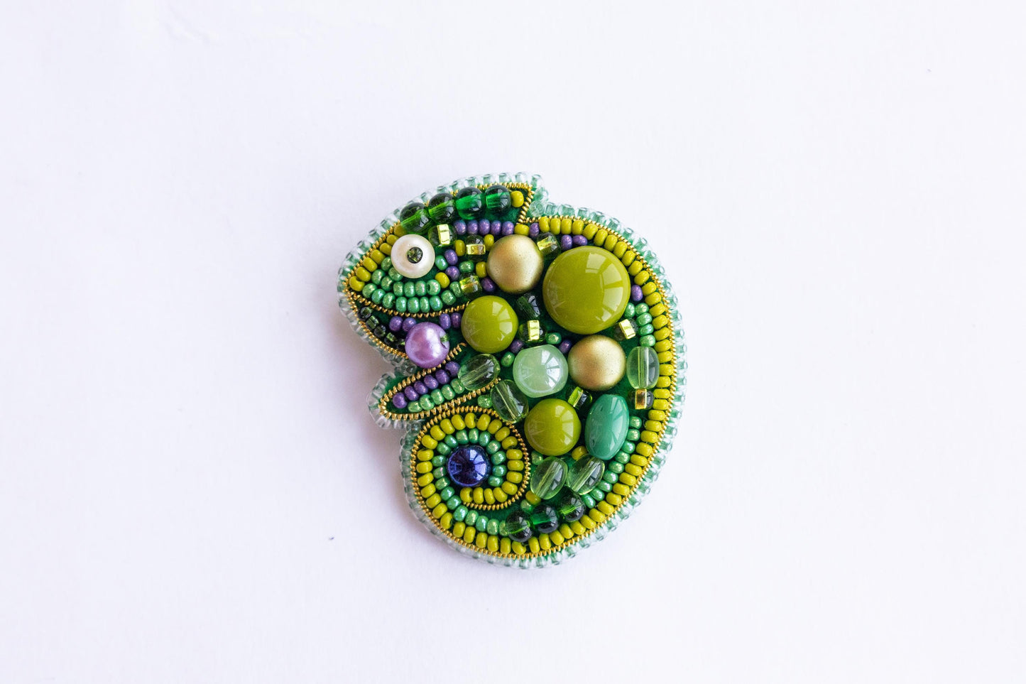 a beaded brooch sitting on top of a white surface