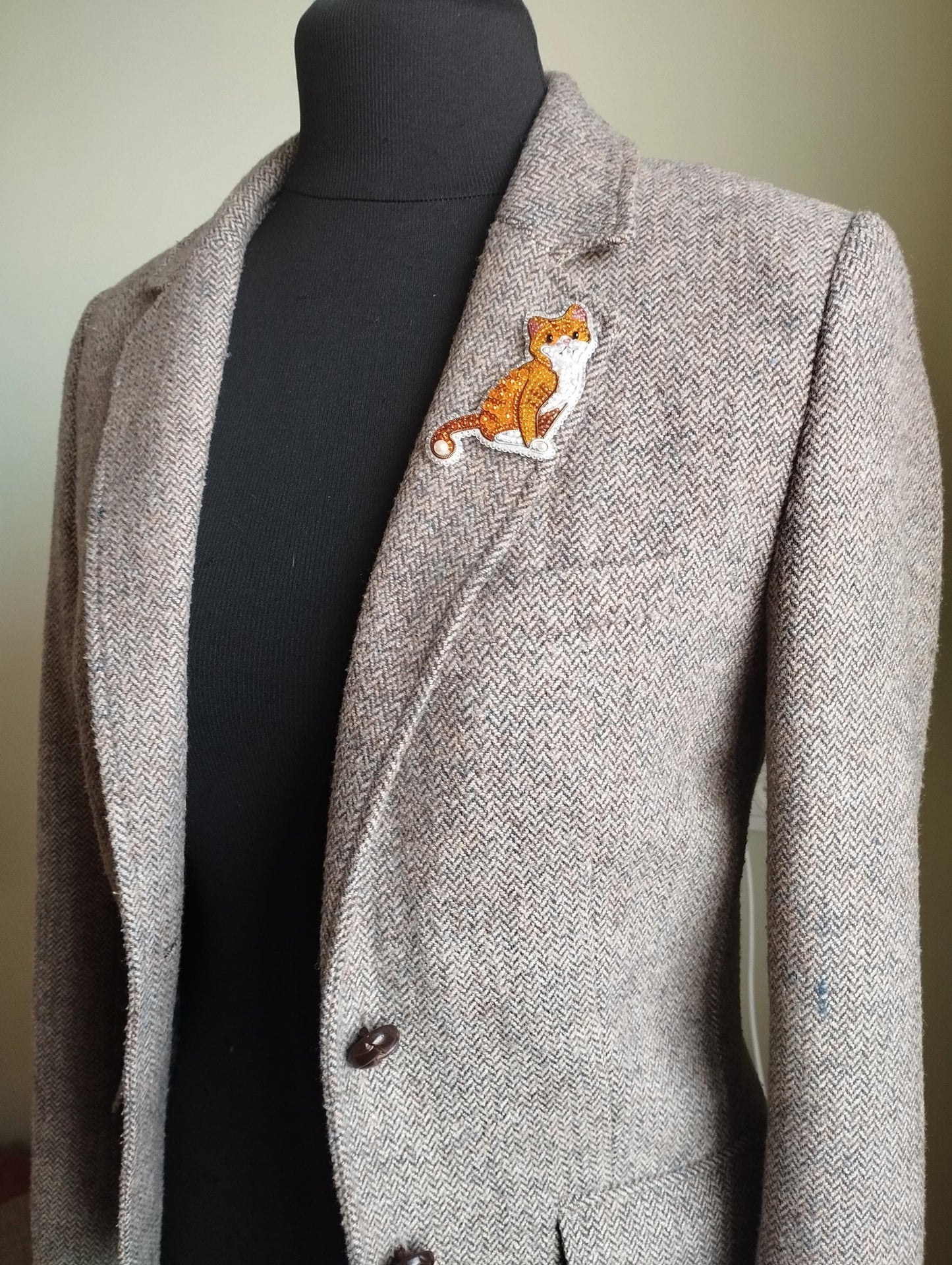 A gray tweed blazer with a cat embroidered patch on the left breast pocket area.
