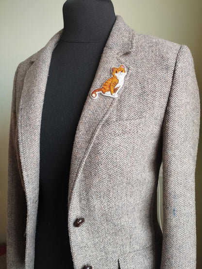 A gray tweed blazer with a cat embroidered patch on the left breast pocket area.