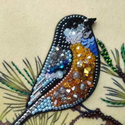 A close-up of a bird-shaped embroidered piece, adorned with various colorful beads and sequins, creating a vibrant and intricate design.