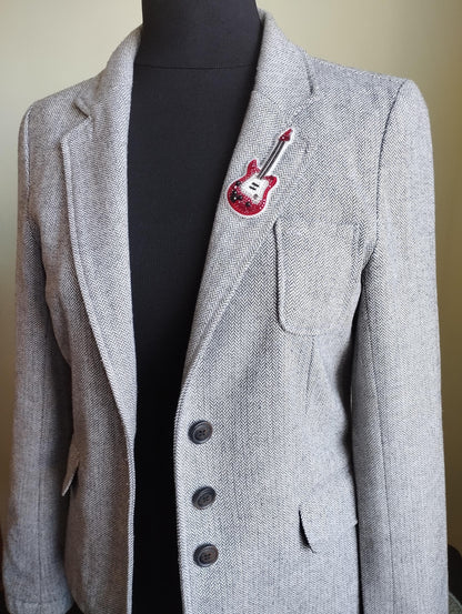 A gray tweed jacket with a red guitar patch on the left breast pocket.