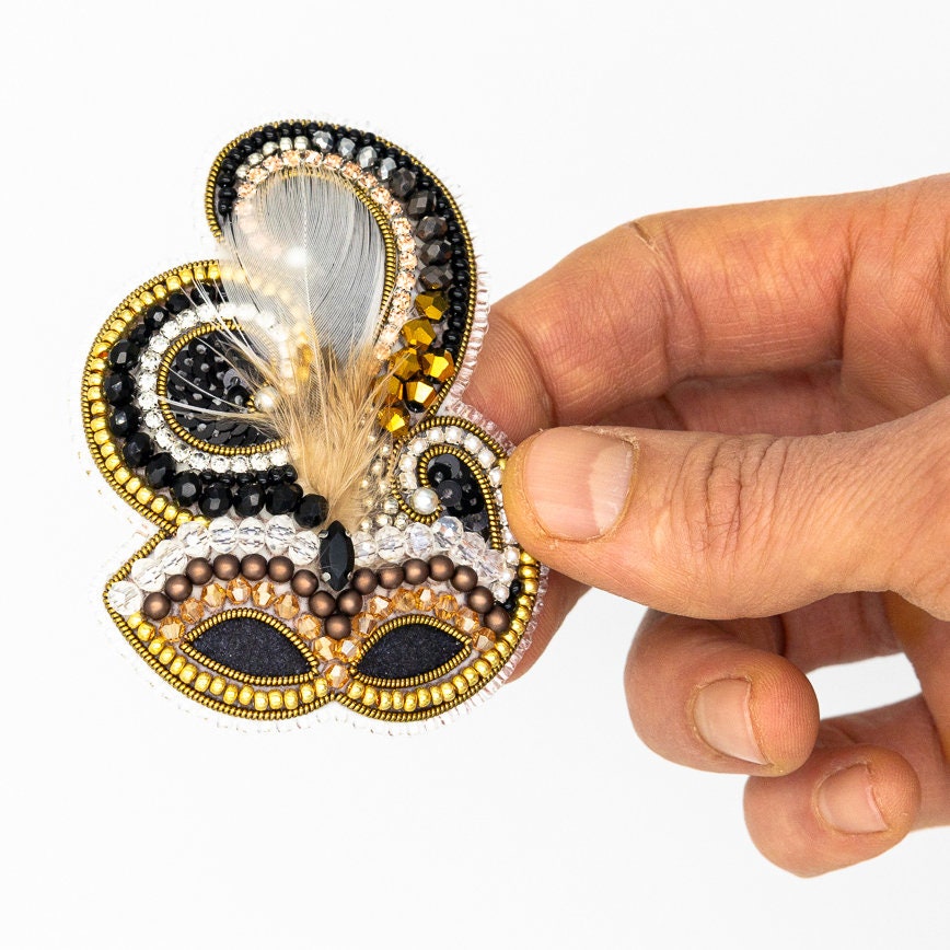 a hand holding a piece of beaded art