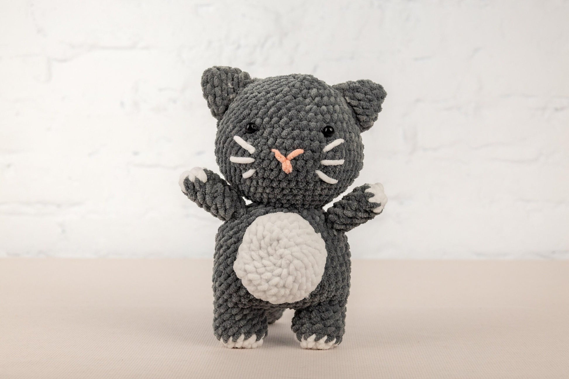 a crocheted black and white cat holding a white ball