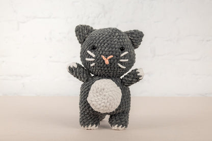 a crocheted black and white cat holding a white ball