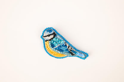 a blue and yellow beaded bird on a white background