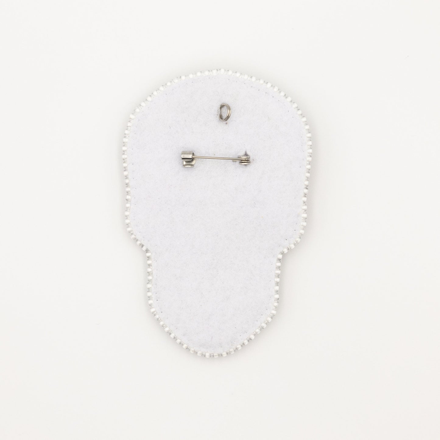 a white brooch with a pin on it