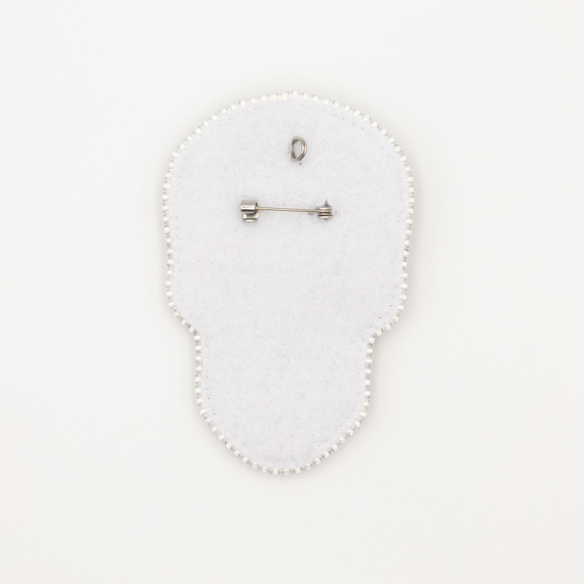 a white brooch with a pin on it