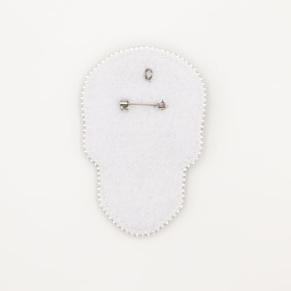 a white brooch with a pin on it