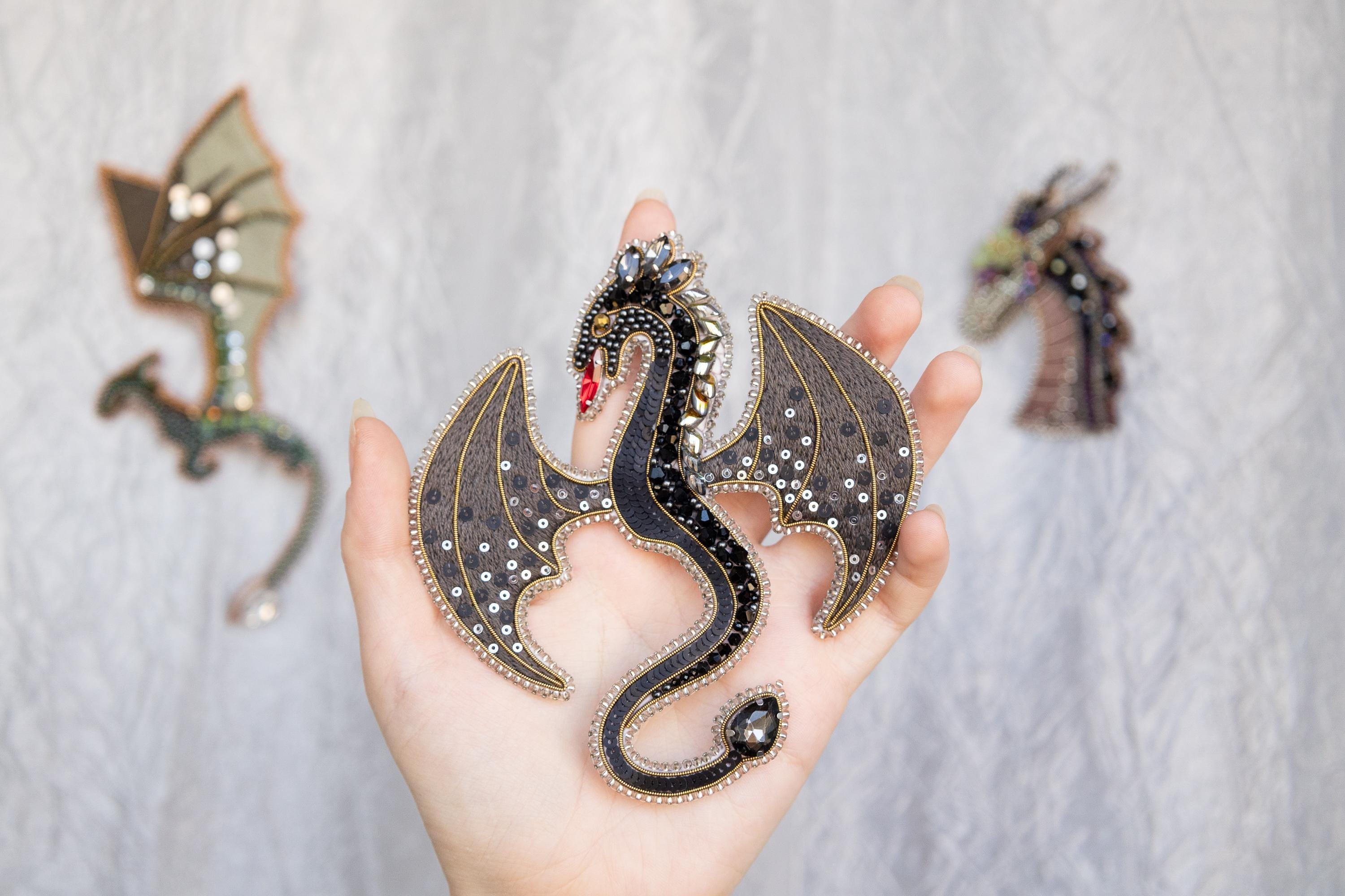 a hand holding a dragon figurine next to other dragon figurines