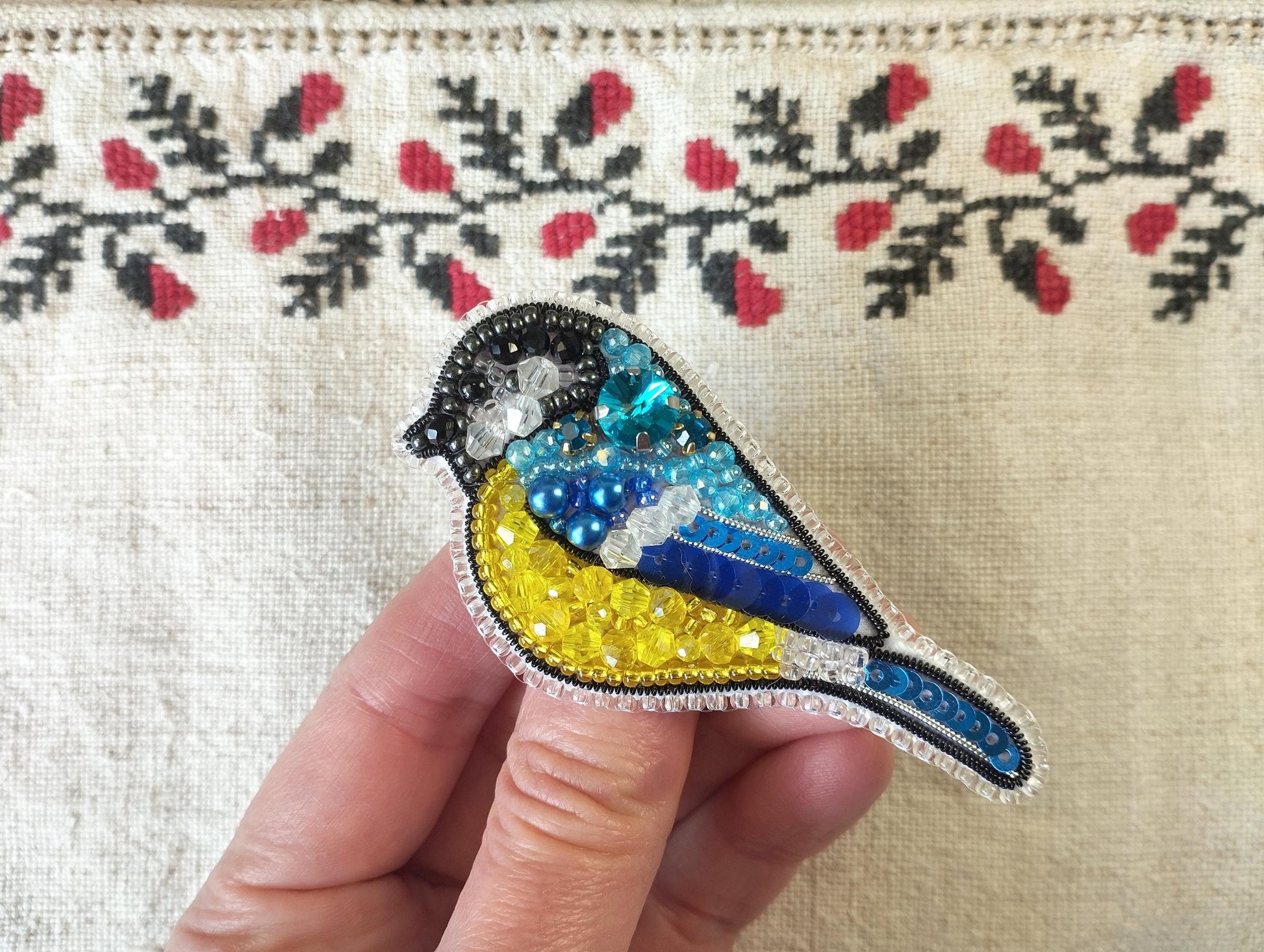 a hand holding a small bird brooch in it&#39;s left hand
