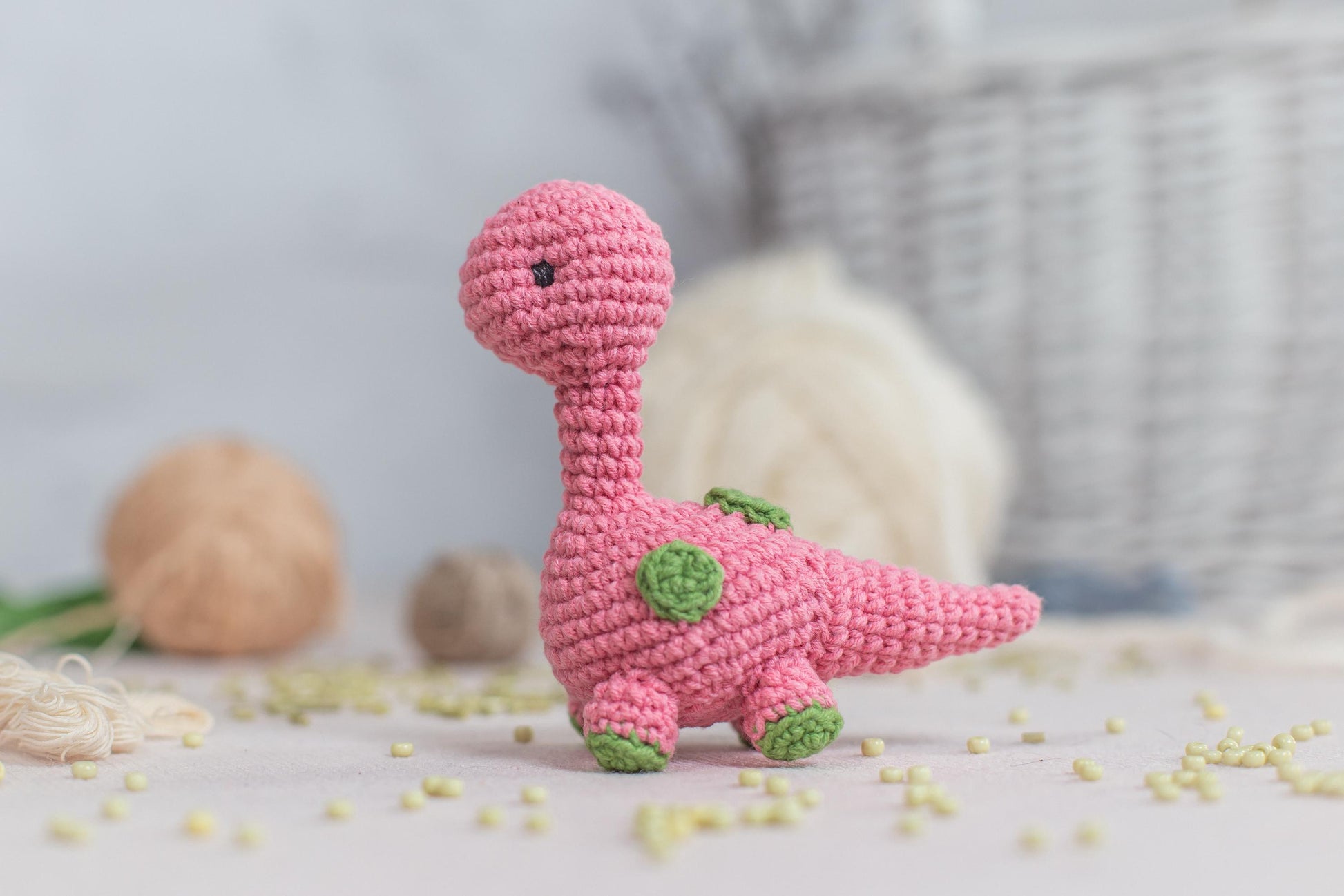 a crocheted pink toy dinosaur sitting on a table