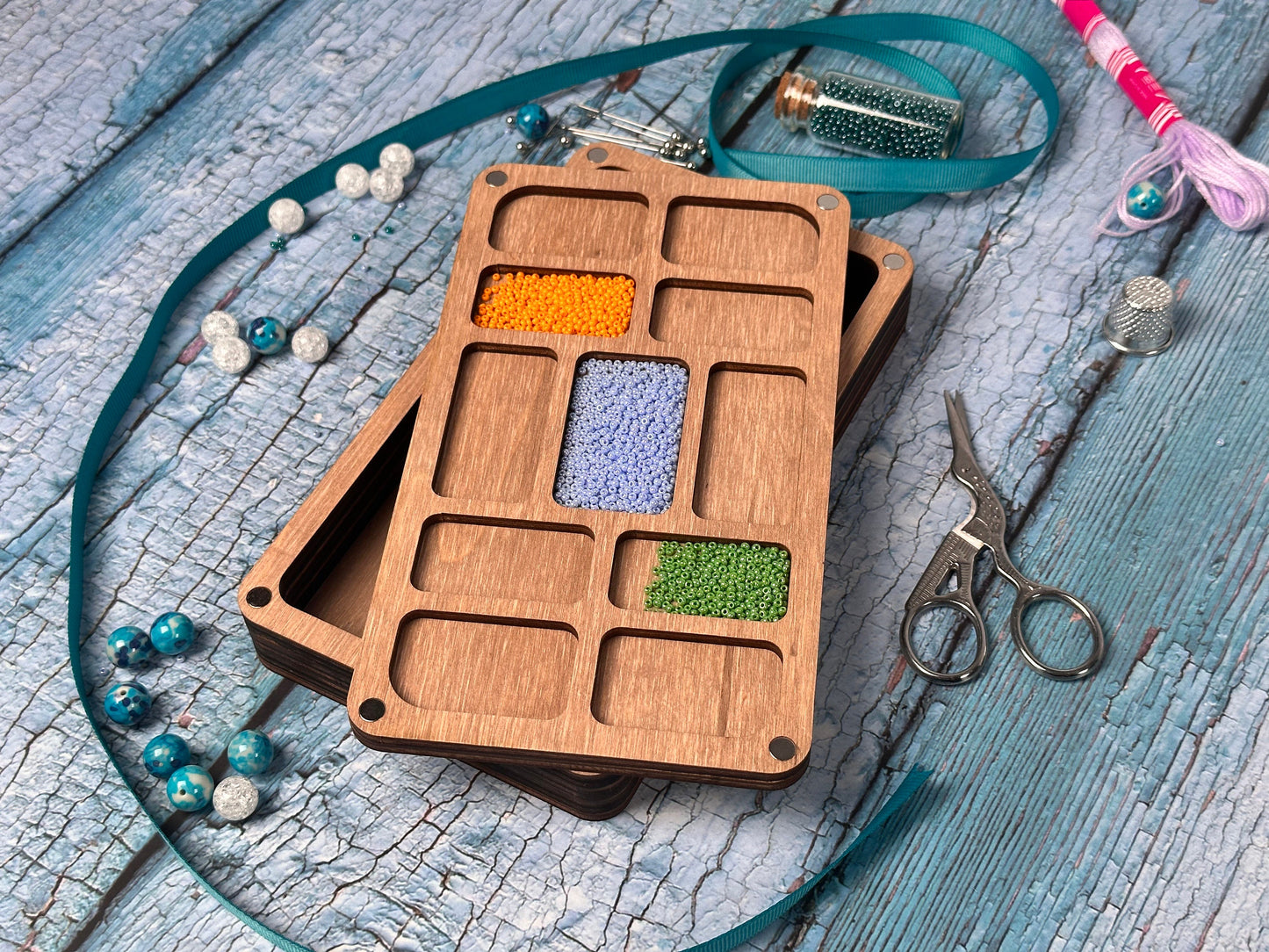 a wooden box with beads and scissors on a table