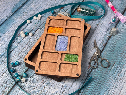 a wooden box with beads and scissors on a table