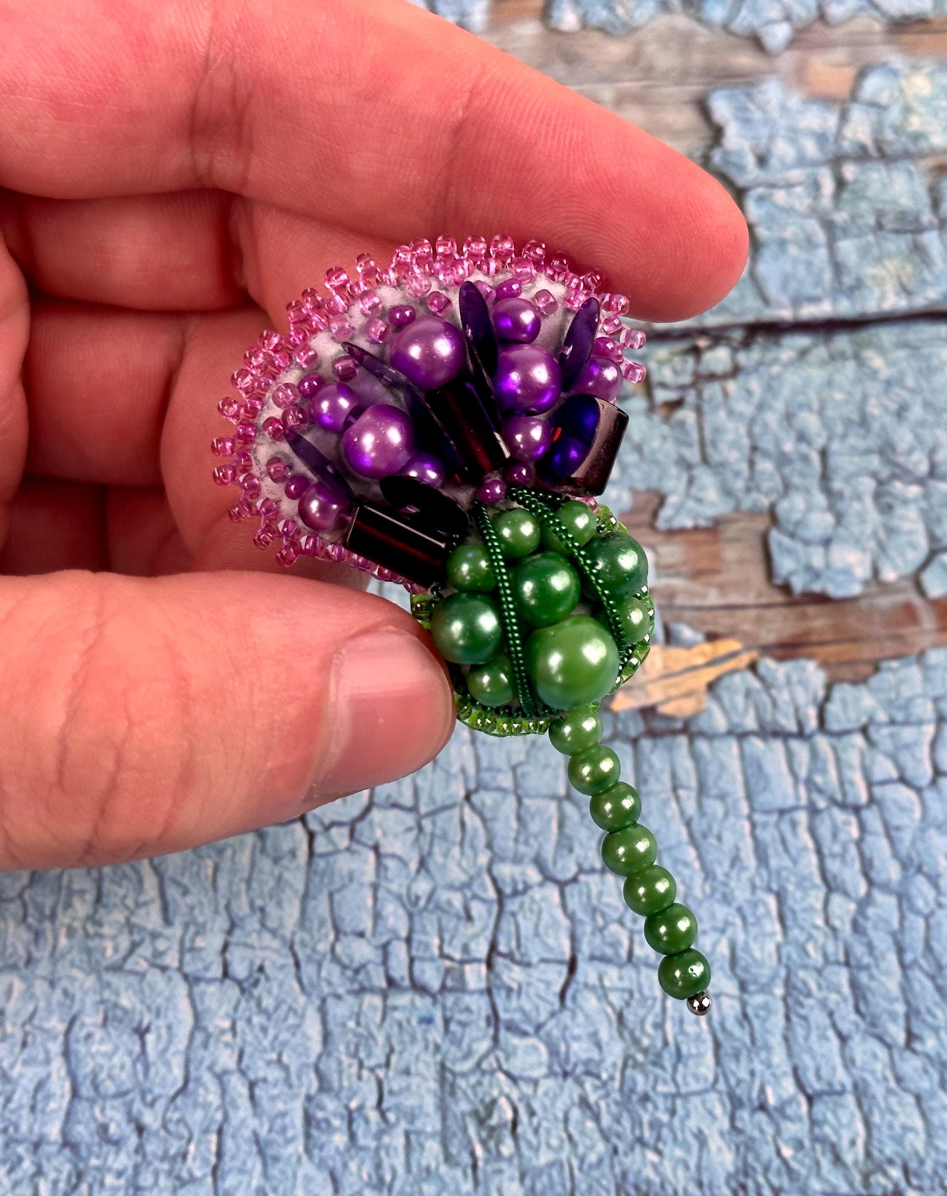 a person holding a beaded flower in their hand