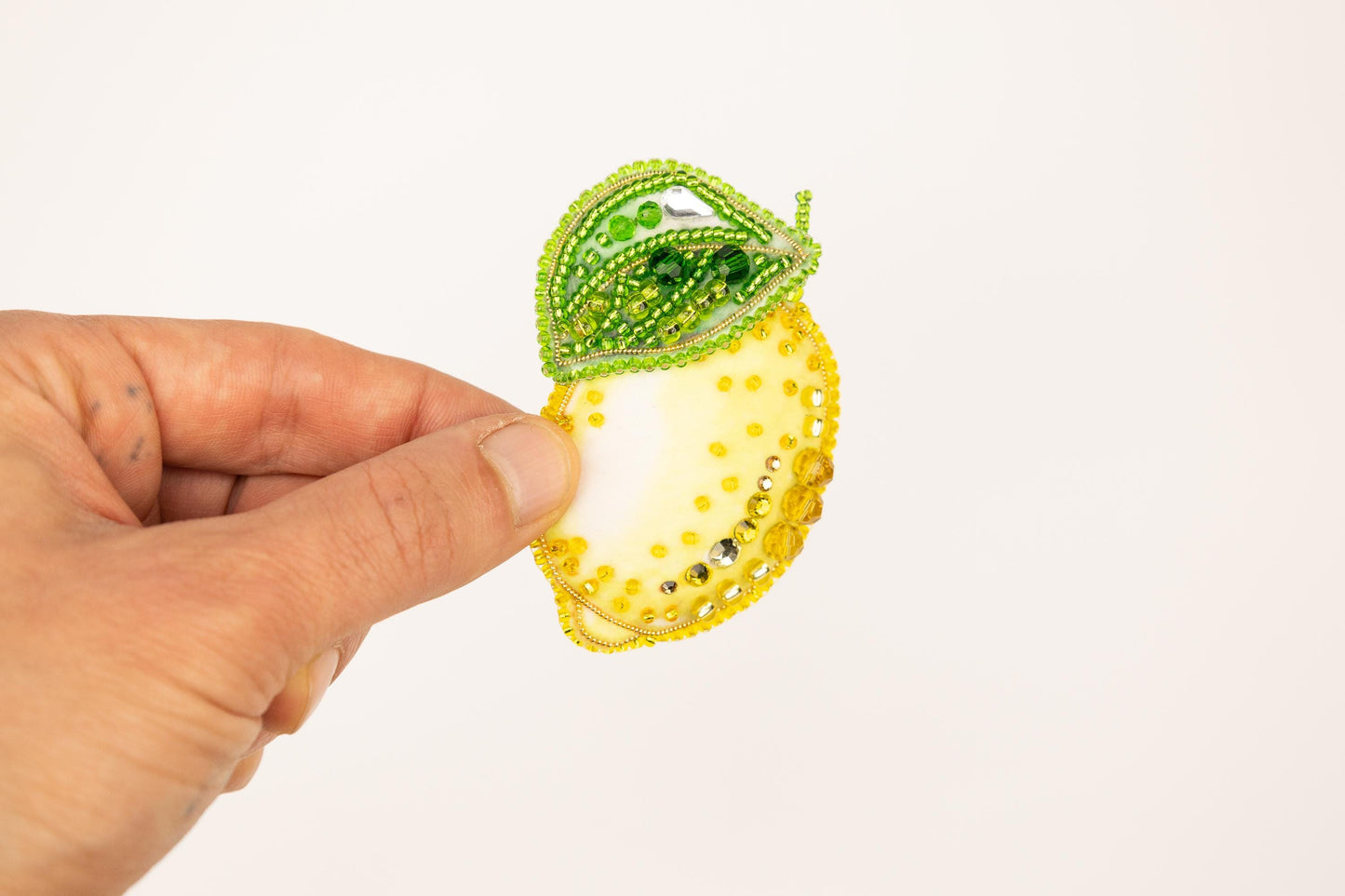 a hand is holding a piece of beaded fruit