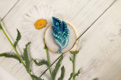 a blue feather brooch sitting on top of a white plate