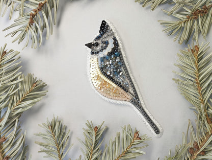 a bird ornament hanging from a pine tree
