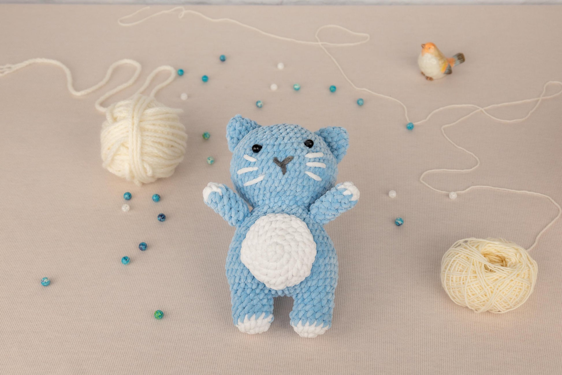 a crocheted blue cat next to a ball of yarn