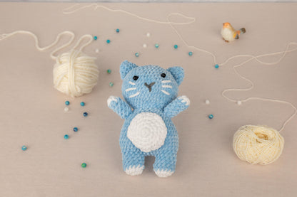 a crocheted blue cat next to a ball of yarn