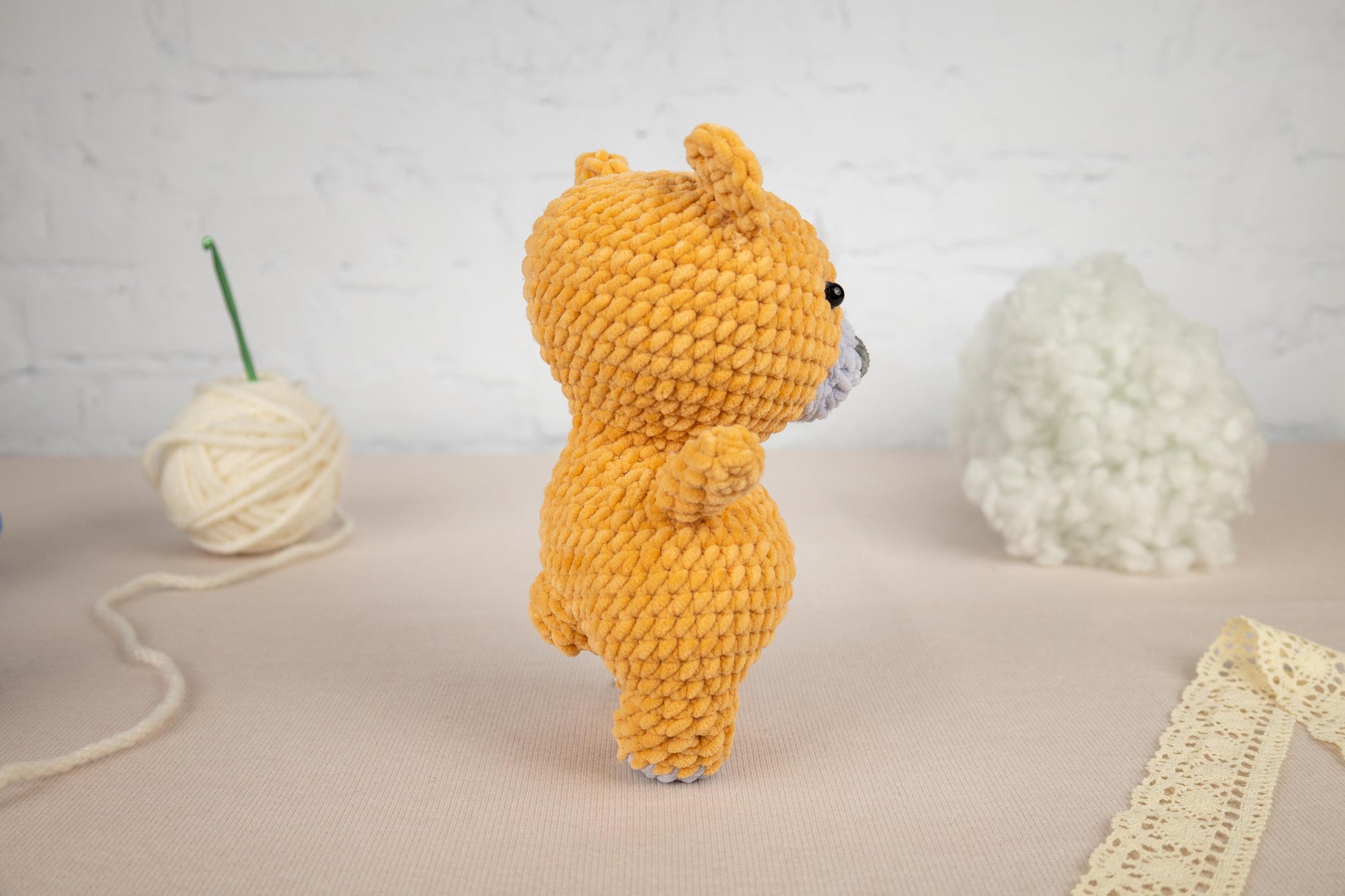 a small yellow teddy bear next to a ball of yarn