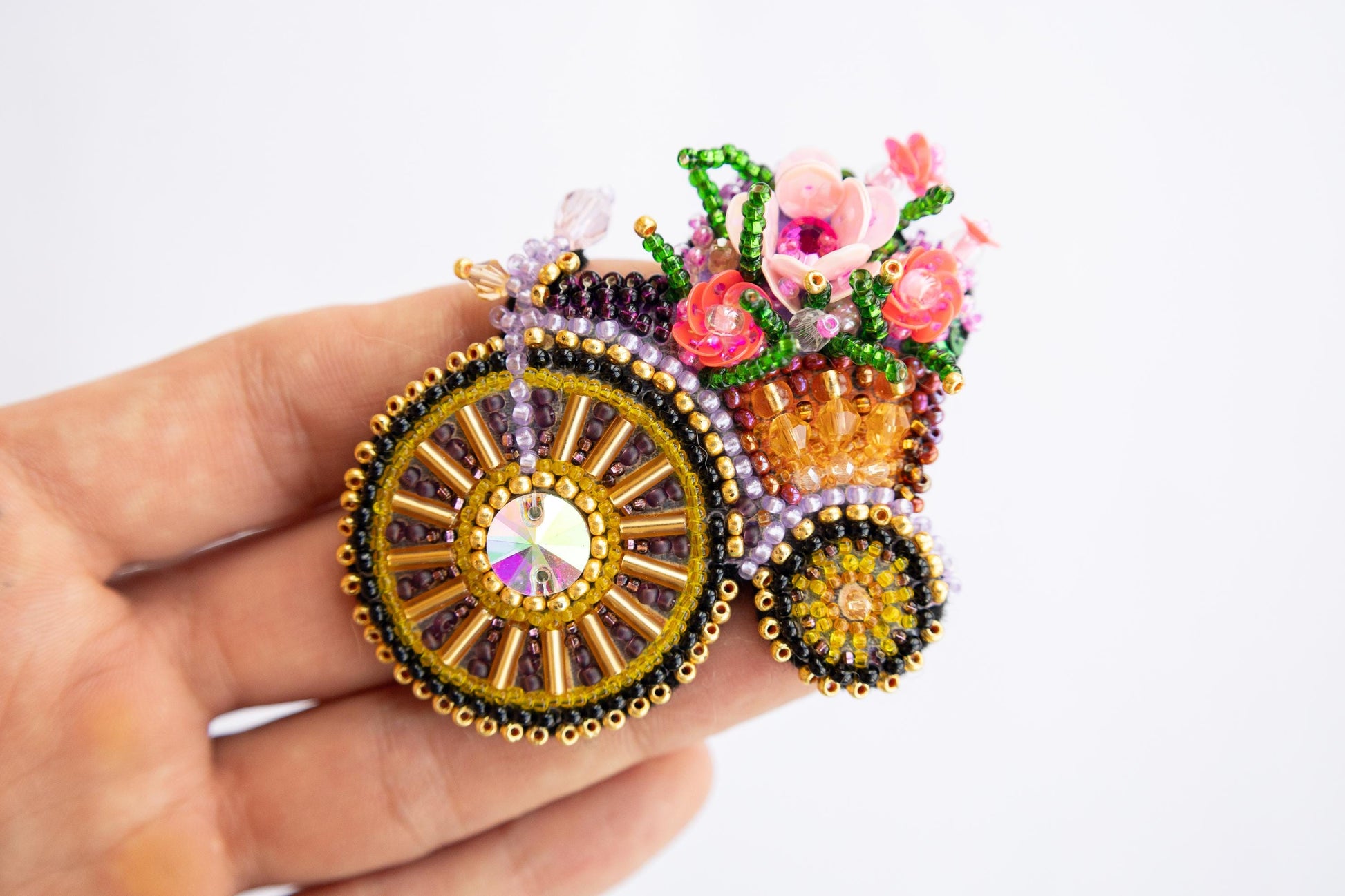 a hand is holding a brooch with flowers on it