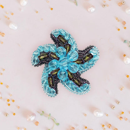 a blue flower brooch sitting on top of a table