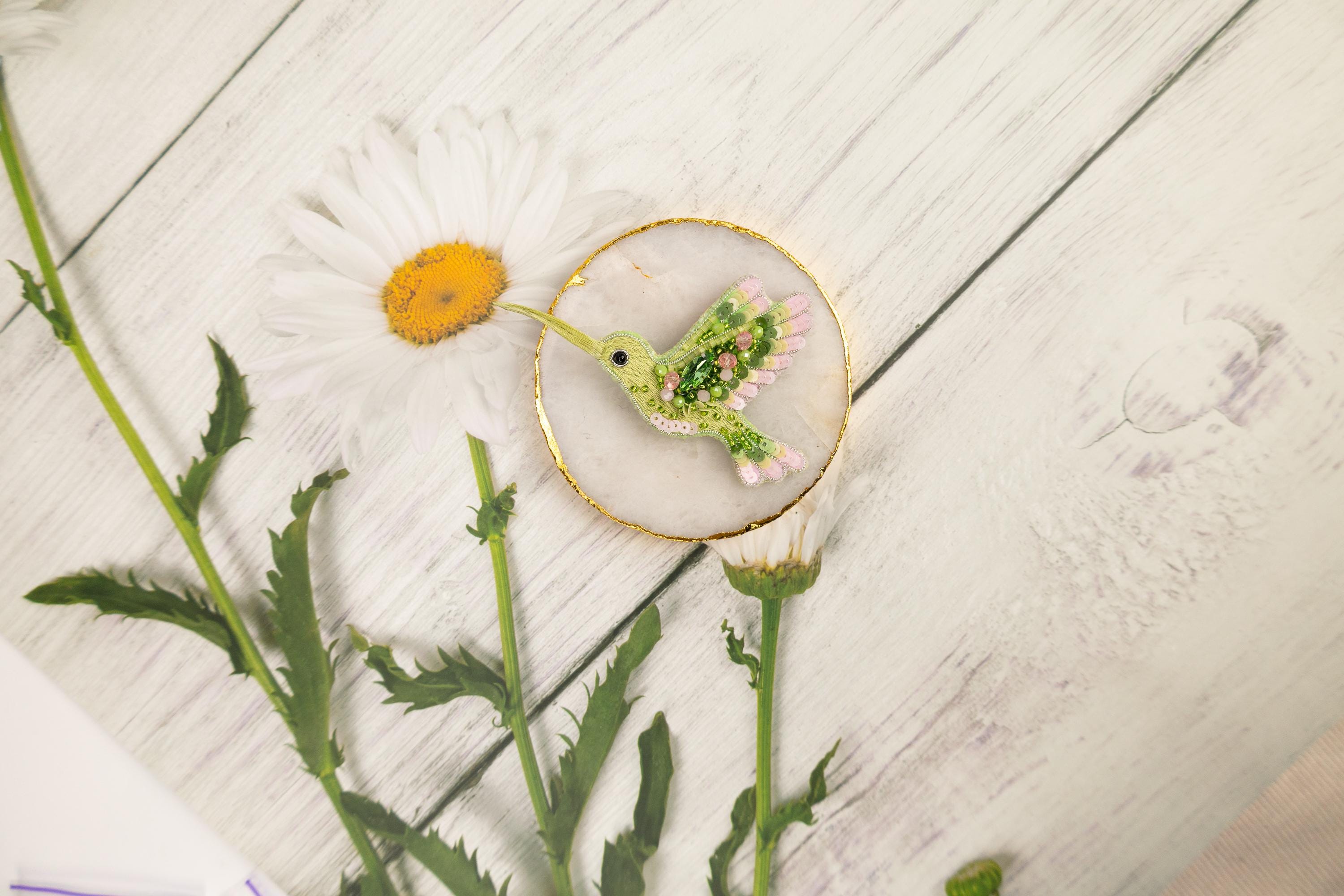 a small bird sitting on top of a plate next to a flower