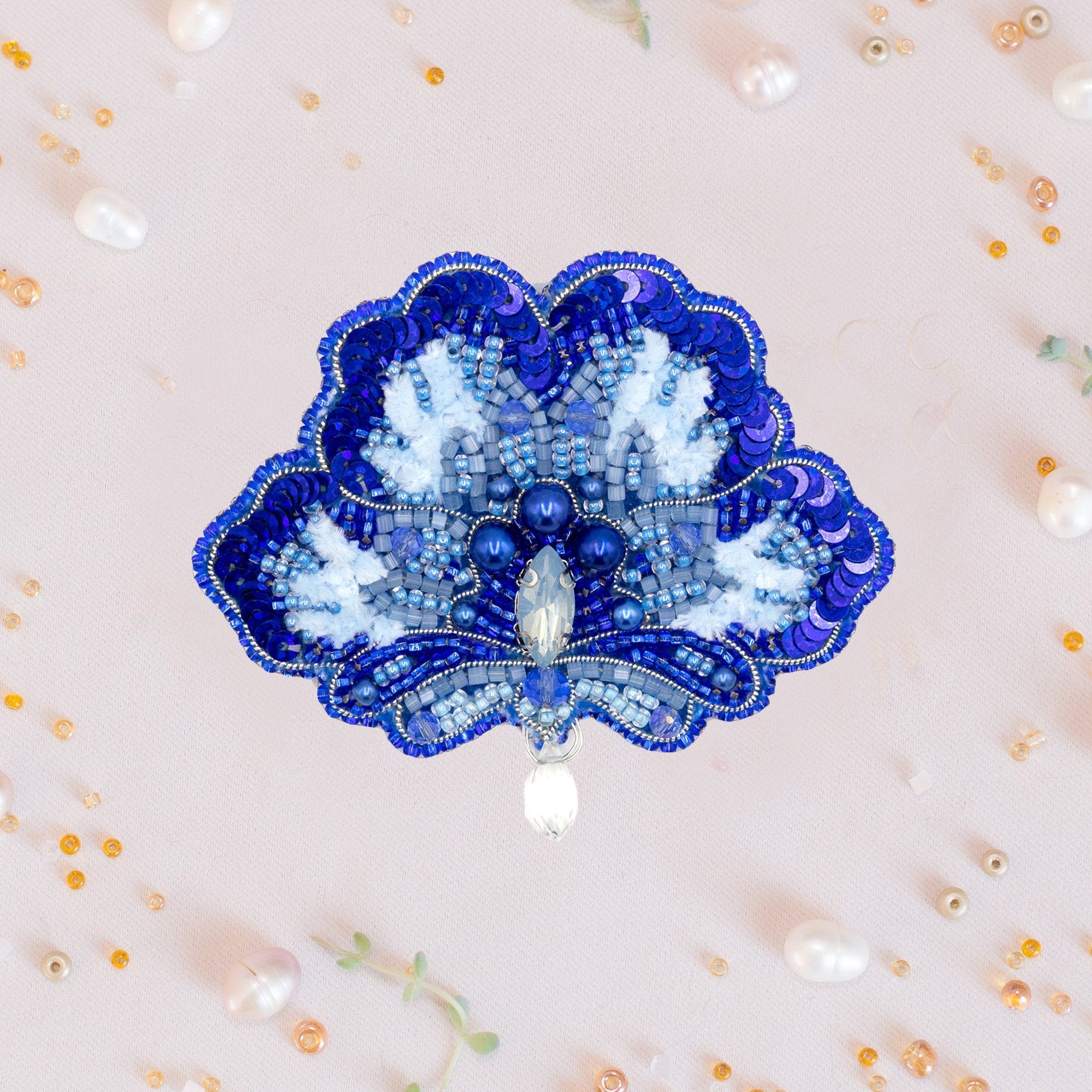 a blue and white brooch sitting on top of a white wall