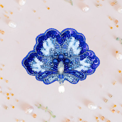a blue and white brooch sitting on top of a white wall